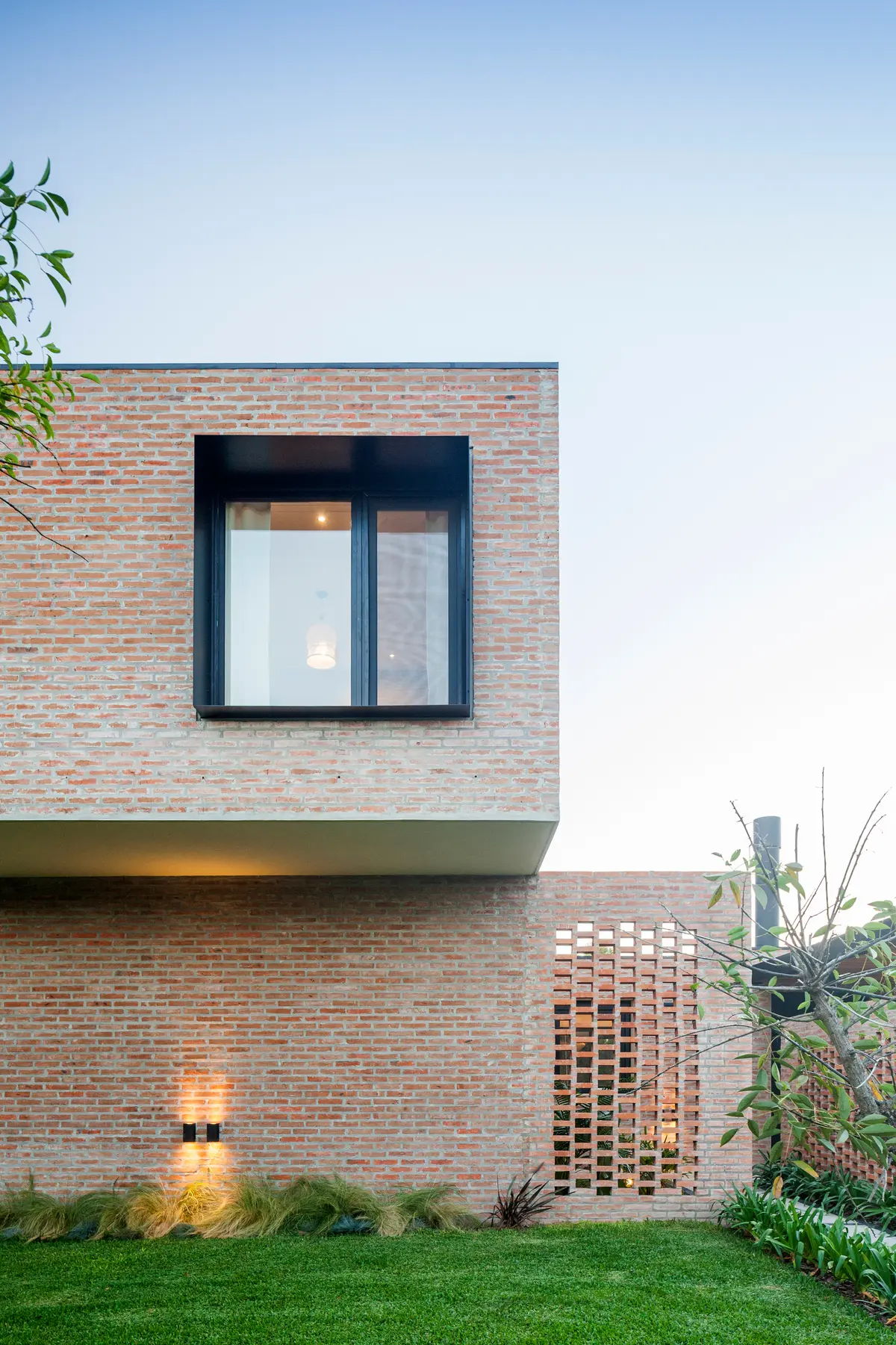 Fachada moderna de ladrillos expuestos con ventana minimalista y luz indirecta — proyecto Casa Brick, por LSA. , en Pilar