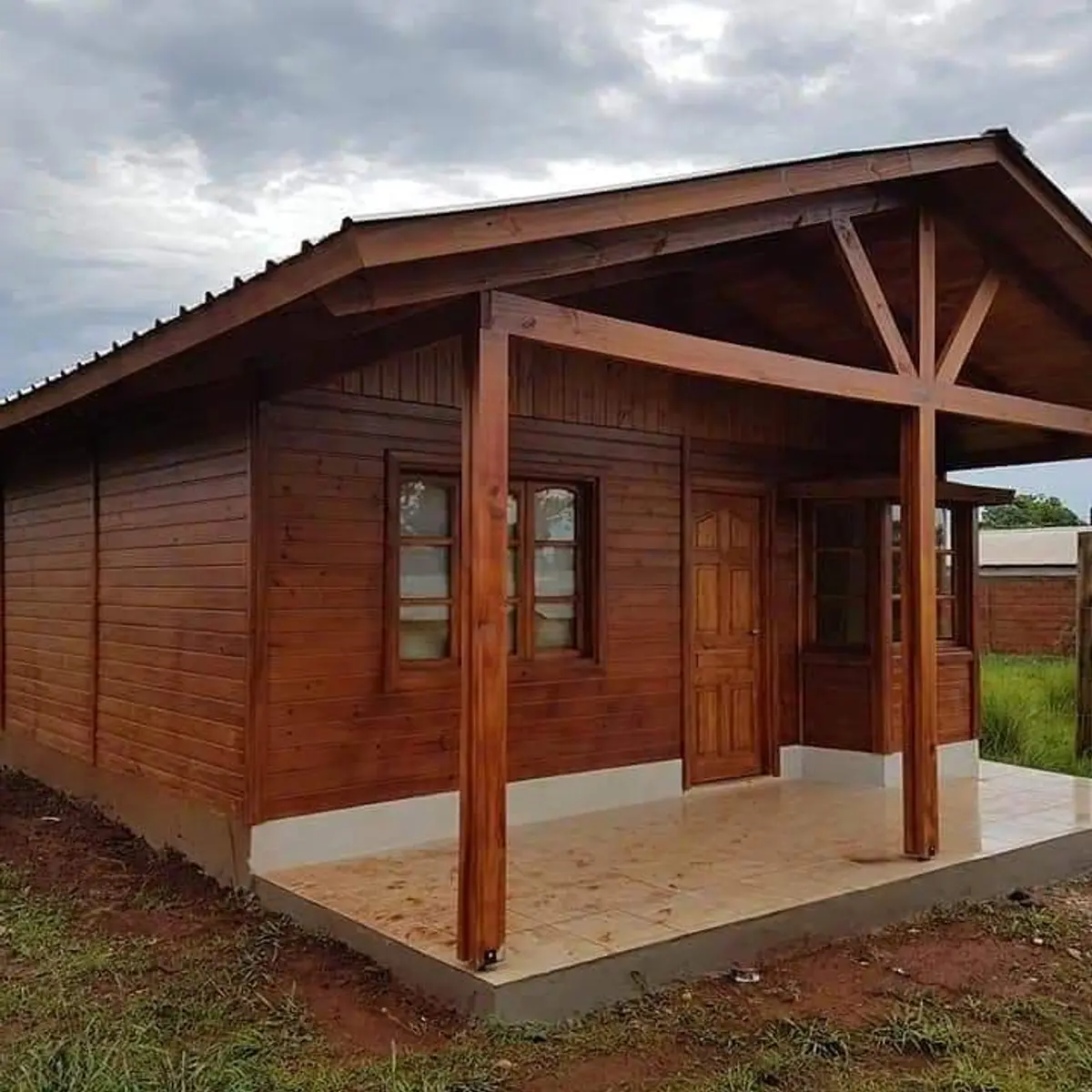 fachada rústica de cabana de madeira com varanda — projeto Muelles y pérgolas, por De madera somos, em Belén de Escobar