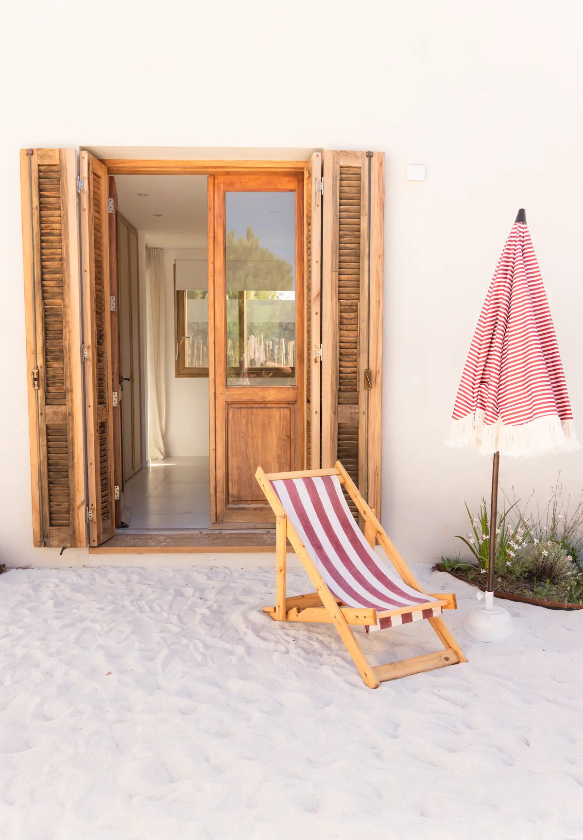 Cadeira de praia listrada e guarda-sol em área externa — projeto El Refugio, por Grupo Pauta Arquitectura, em Pinamar