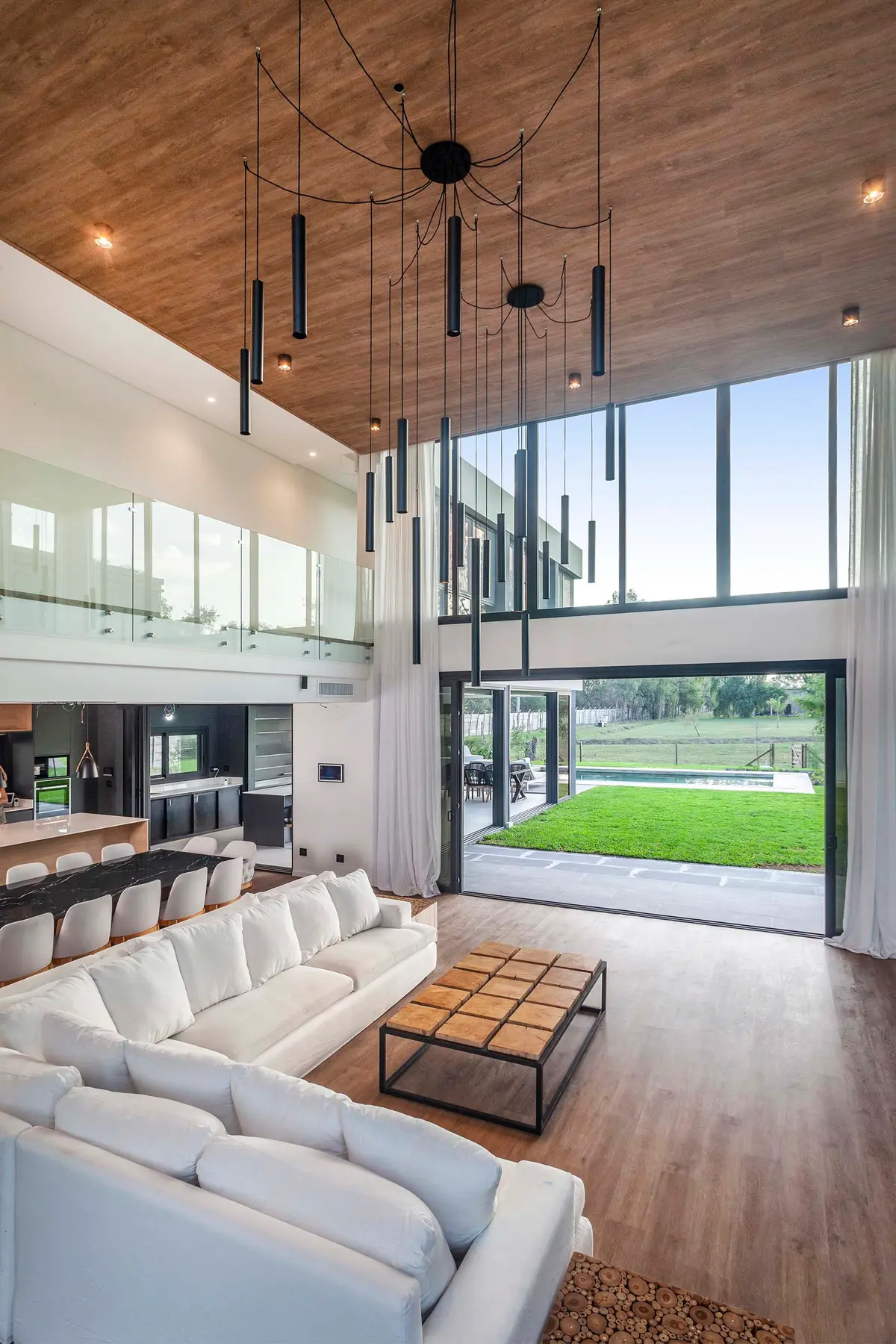 Sala de estar moderna de pé-direito duplo com vista para o jardim e lustre escultural — projeto CASA T199, por A'PRIMA - Arquitectura Sustentable, em Los Robles 5901