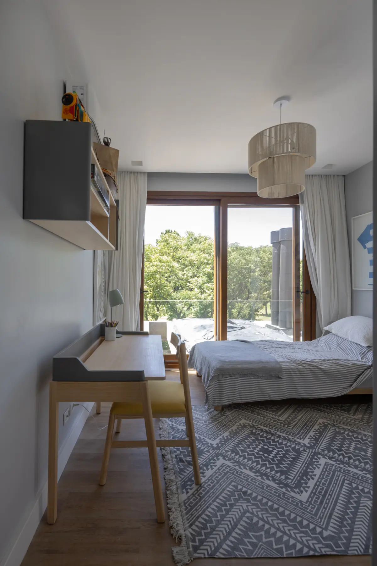 Dormitorio moderno con escritorio, ventana grande al bosque y lámpara tejida — proyecto CASA BaCa, por Alfredo Orfila arquitectura, en Benavidez