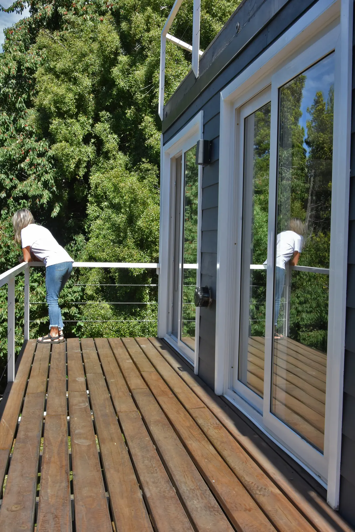 Mulher em varanda de madeira com vista para floresta e janelas amplas — projeto Departamento CV, por Quetuna Interiores, em San Carlos de Bariloche
