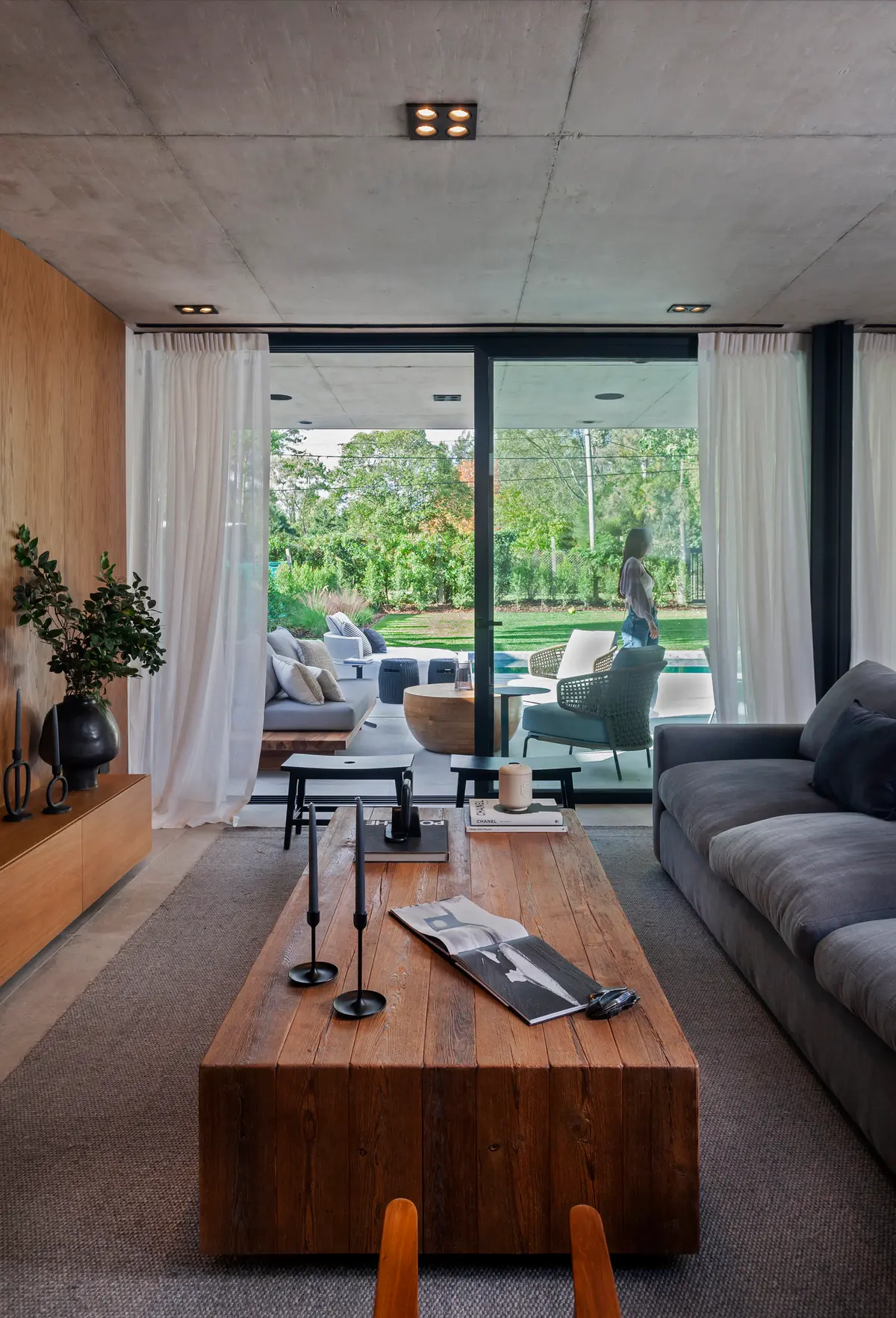Living moderno con techo de hormigón visto y patio exterior — proyecto CASA AH, por GMARQ, en Garin