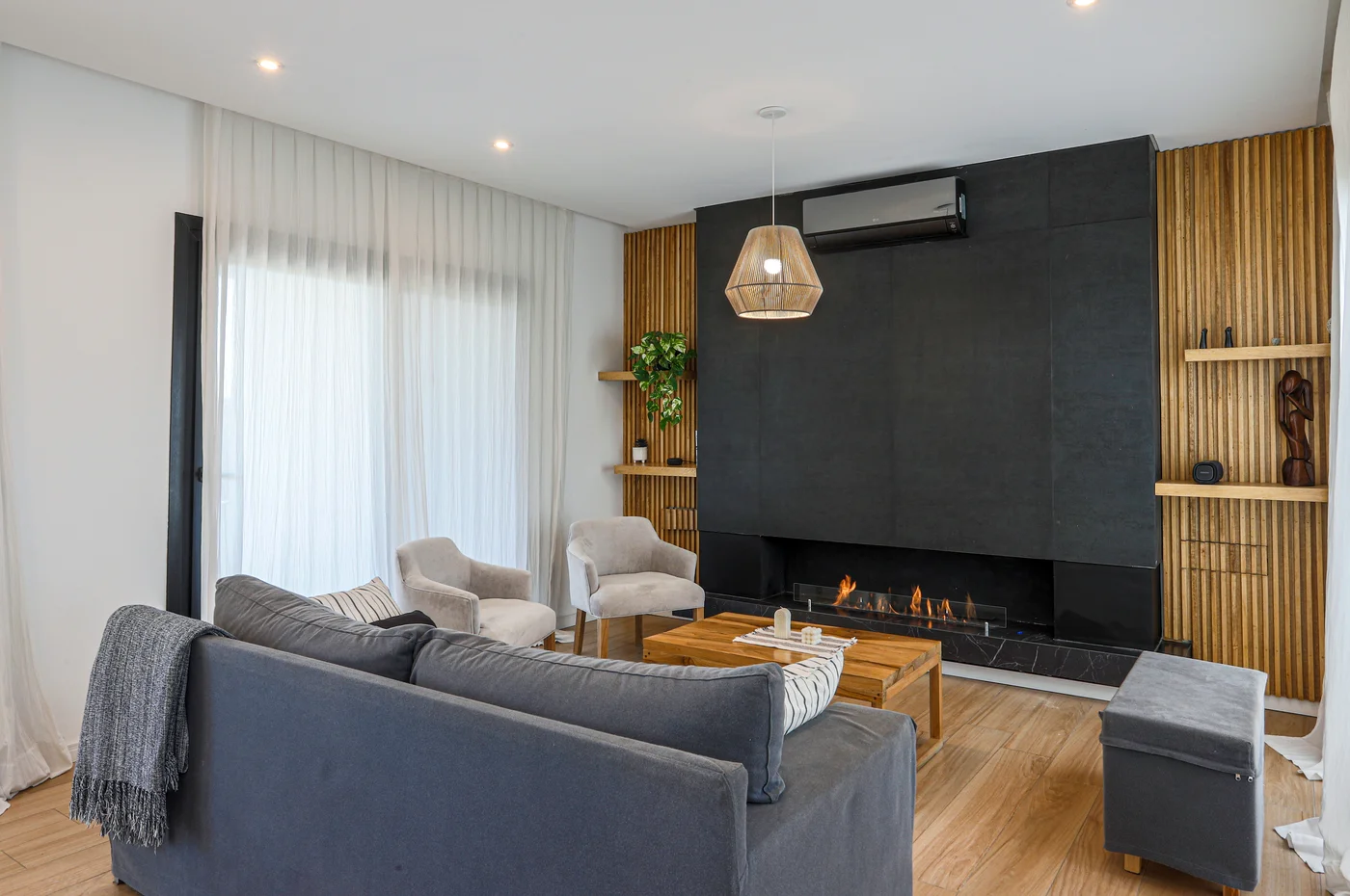 Living moderno con chimenea negra y pared de madera