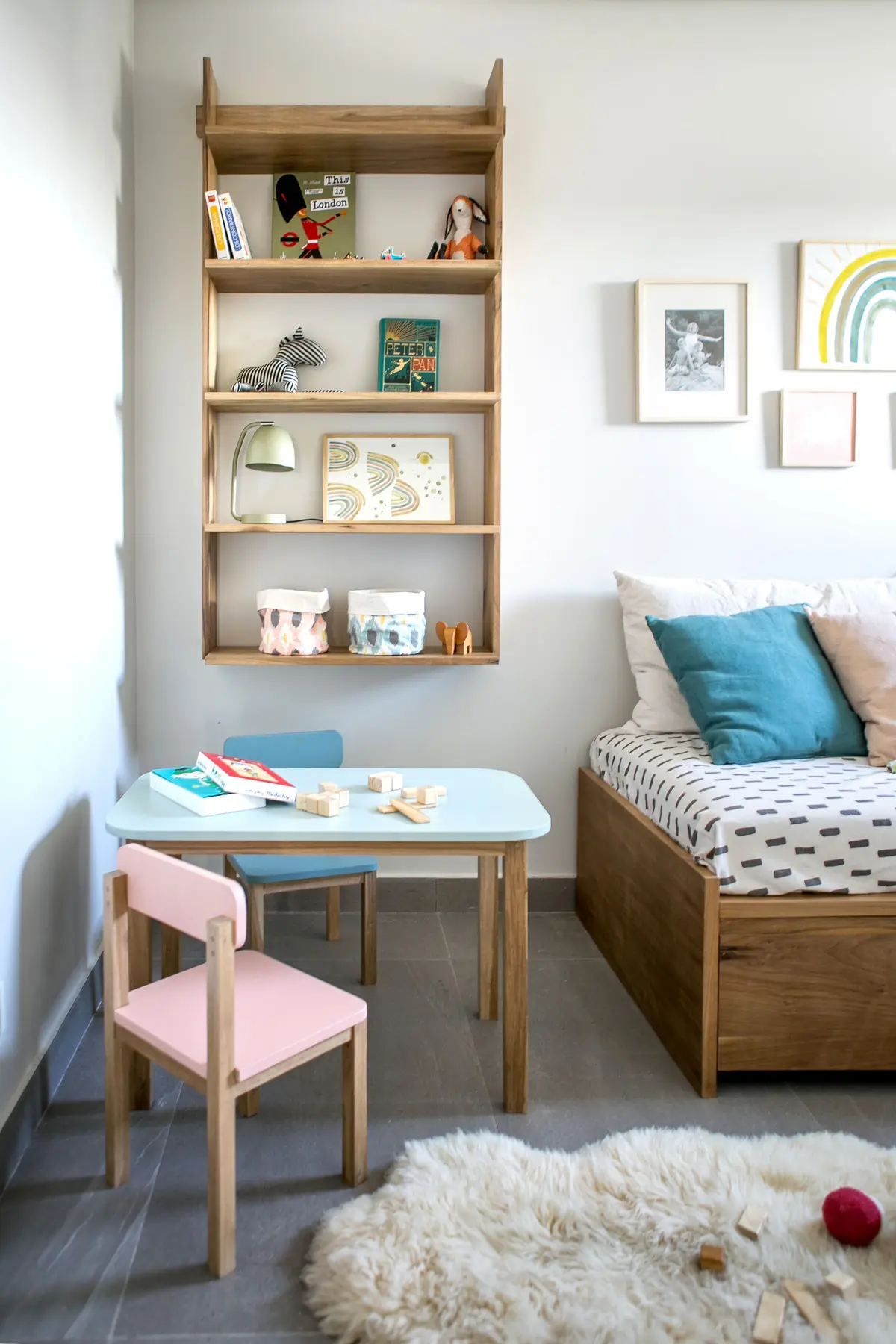 Quarto infantil escandinavo com mesa azul, cadeira rosa e prateleira de madeira — projeto BA 2 2018, por Mesopotamia Ba, em CABA