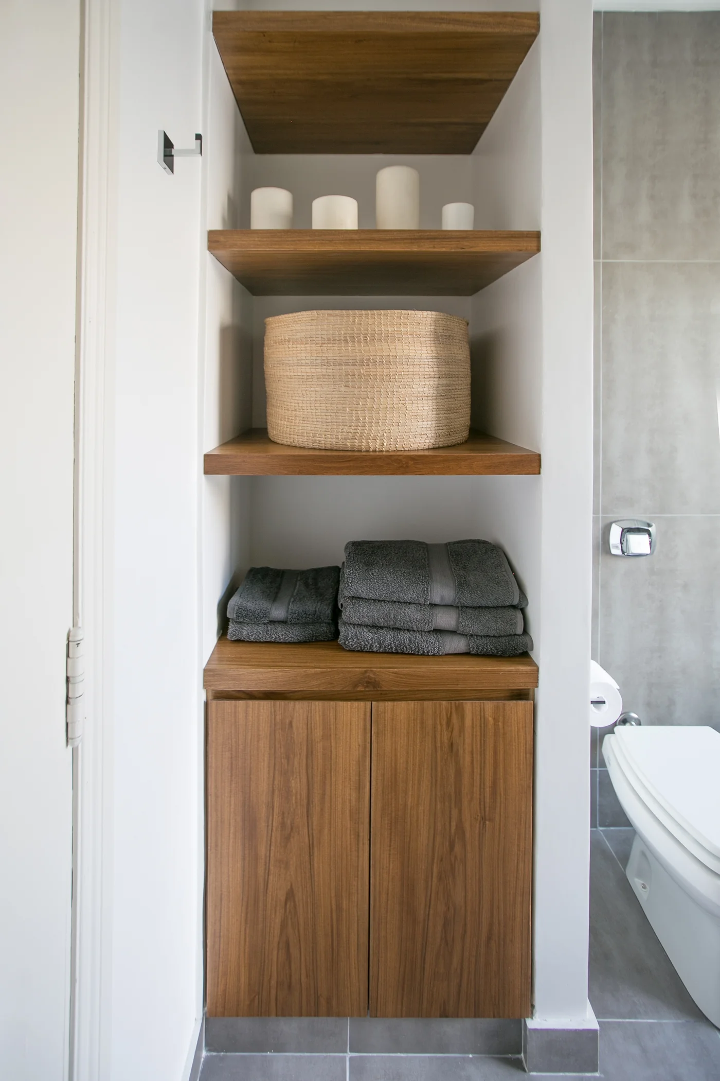 Baño moderno con mueble de madera y almacenamiento integrado.