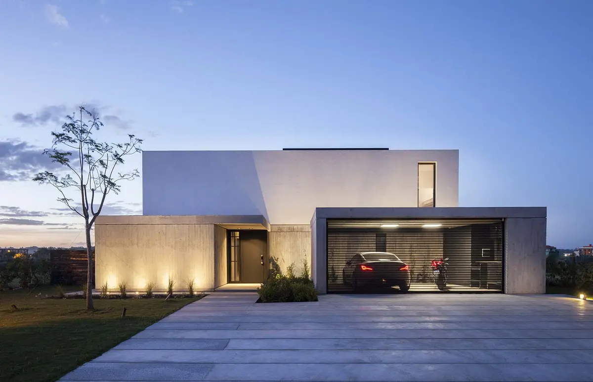 Fachada moderna de concreto com garagem envidraçada e carro esportivo — projeto CASA N, por GMARQ