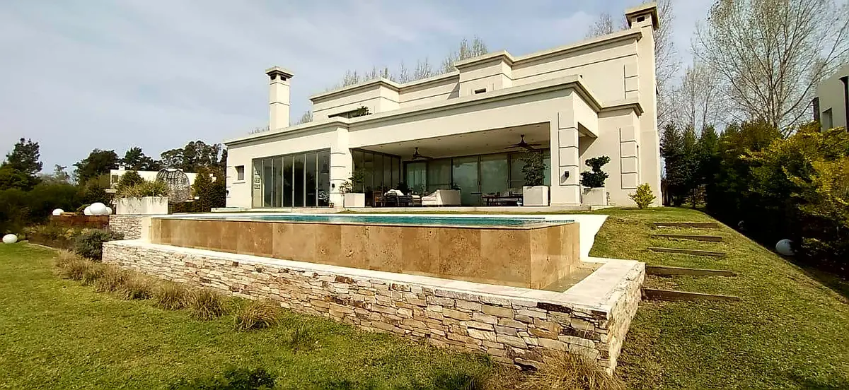Casa moderna de lujo con piscina infinita y fachada de piedra — proyecto LRCC 249, por LESSI ARQUITECTURA, en Los Cardales