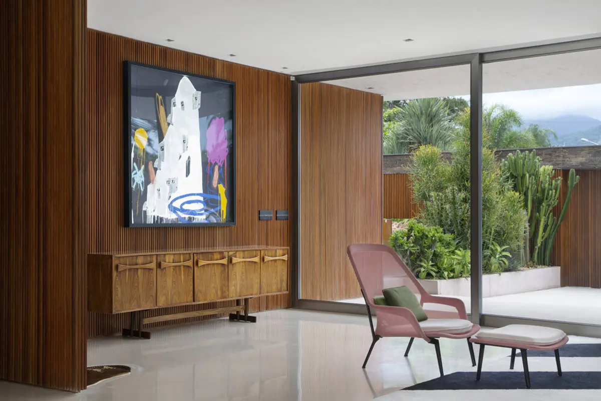 Living moderno con pared de madera, sillones de cuero y vista al jardín — proyecto BM House, por Studio Ro-ca