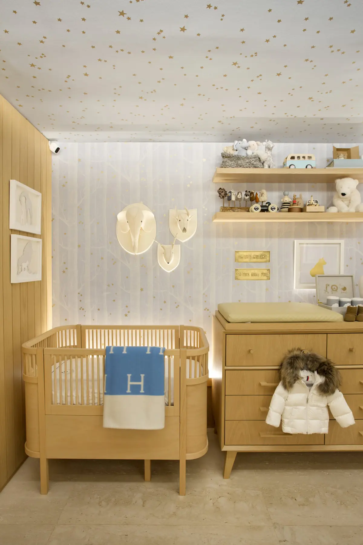 Habitación infantil nórdica con cuna redonda de madera y estrellas doradas — proyecto Quarto Bernardo, por Studio Ro-ca