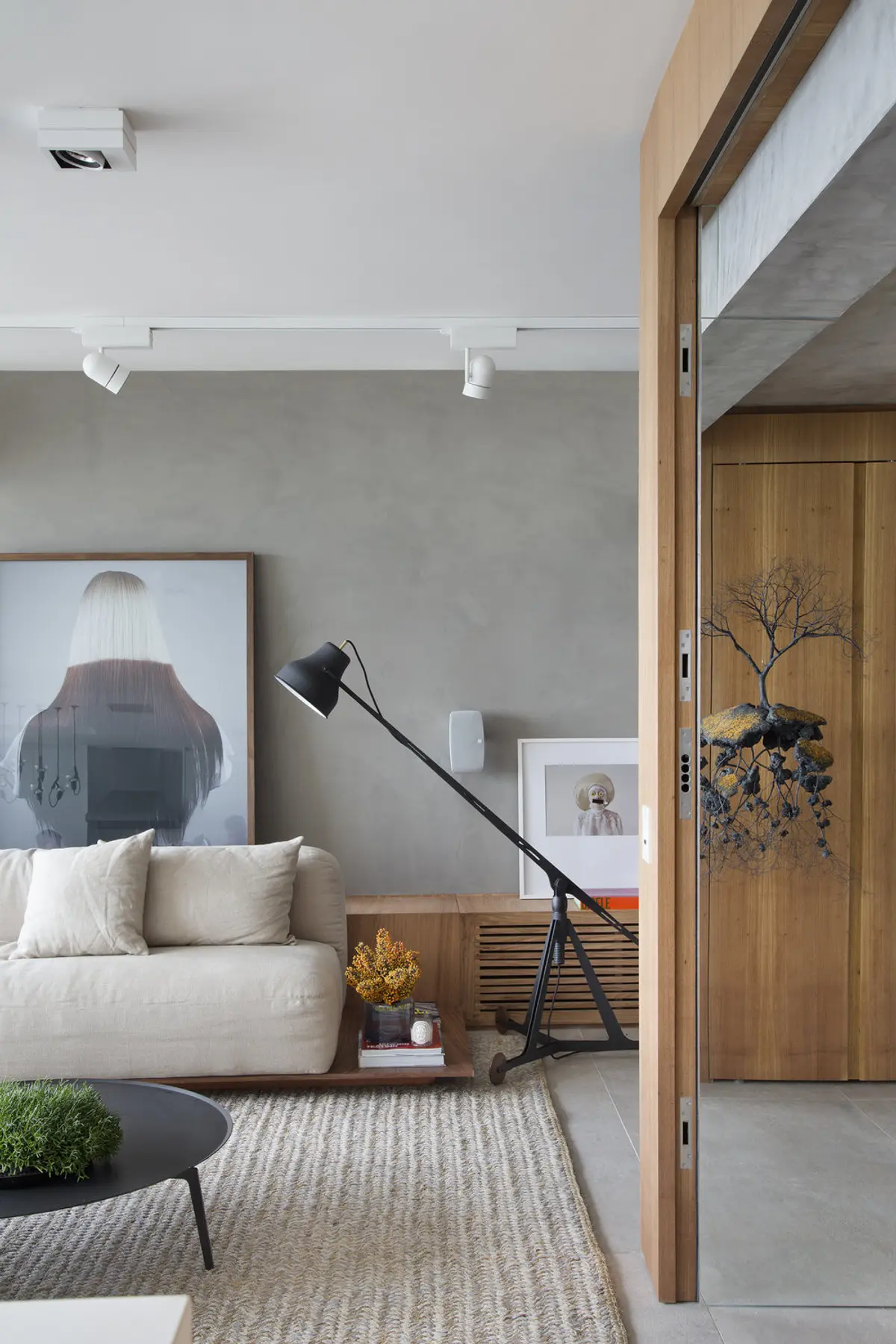 Living moderno con sofá blanco, pared hormigón y puerta madera — proyecto PL House, por Studio Ro-ca