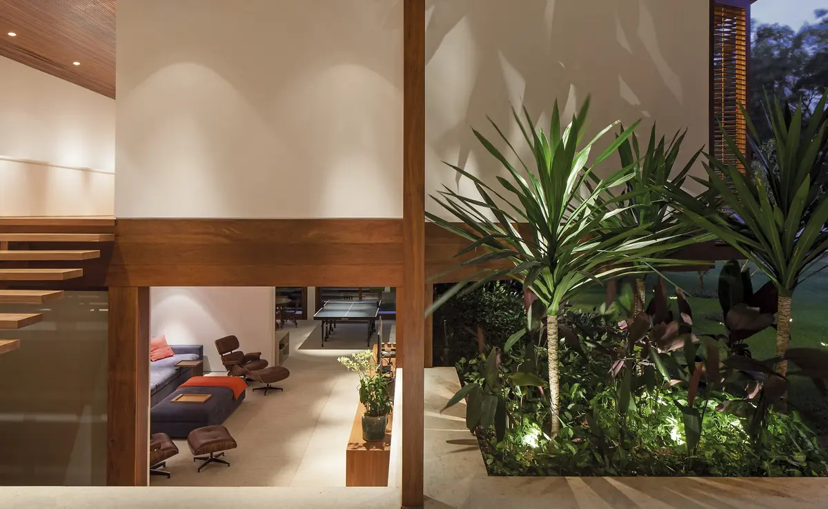 Pasillo con escalera, doble altura y plantas naturales junto ventanal — proyecto Residência GS, por Gil Fialho