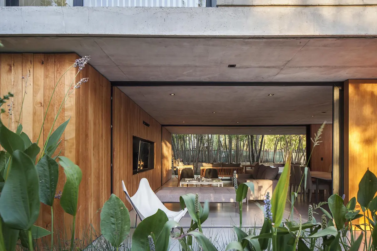 Fachada moderna con revestimiento de madera y silla mariposa — proyecto Casa MF, por V2 Arquitectos, en City Bell