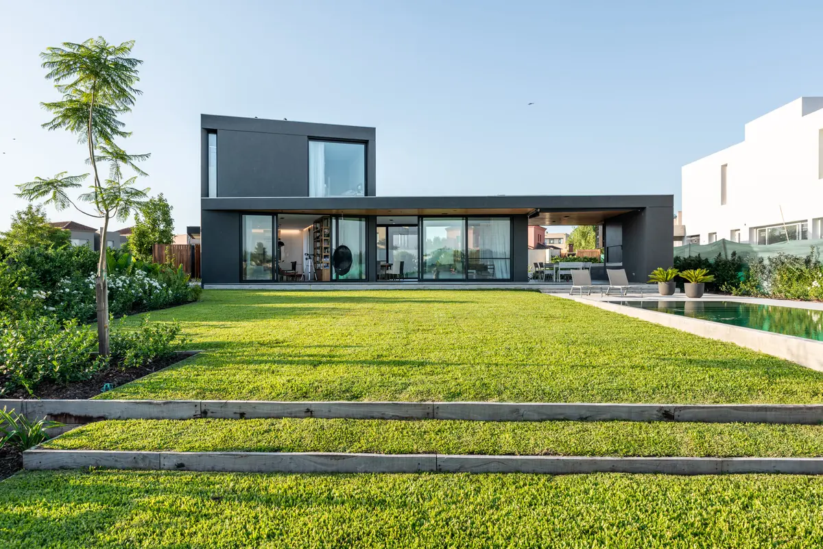 Fachada moderna com piscina e jardim exuberante — projeto Casa BTI, por BDB Arquitectos