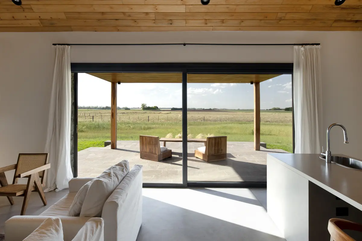 Sala de estar moderna com janelões e teto de madeira, vista para paisagem rural — projeto Campo Cria, por Estudio Lak