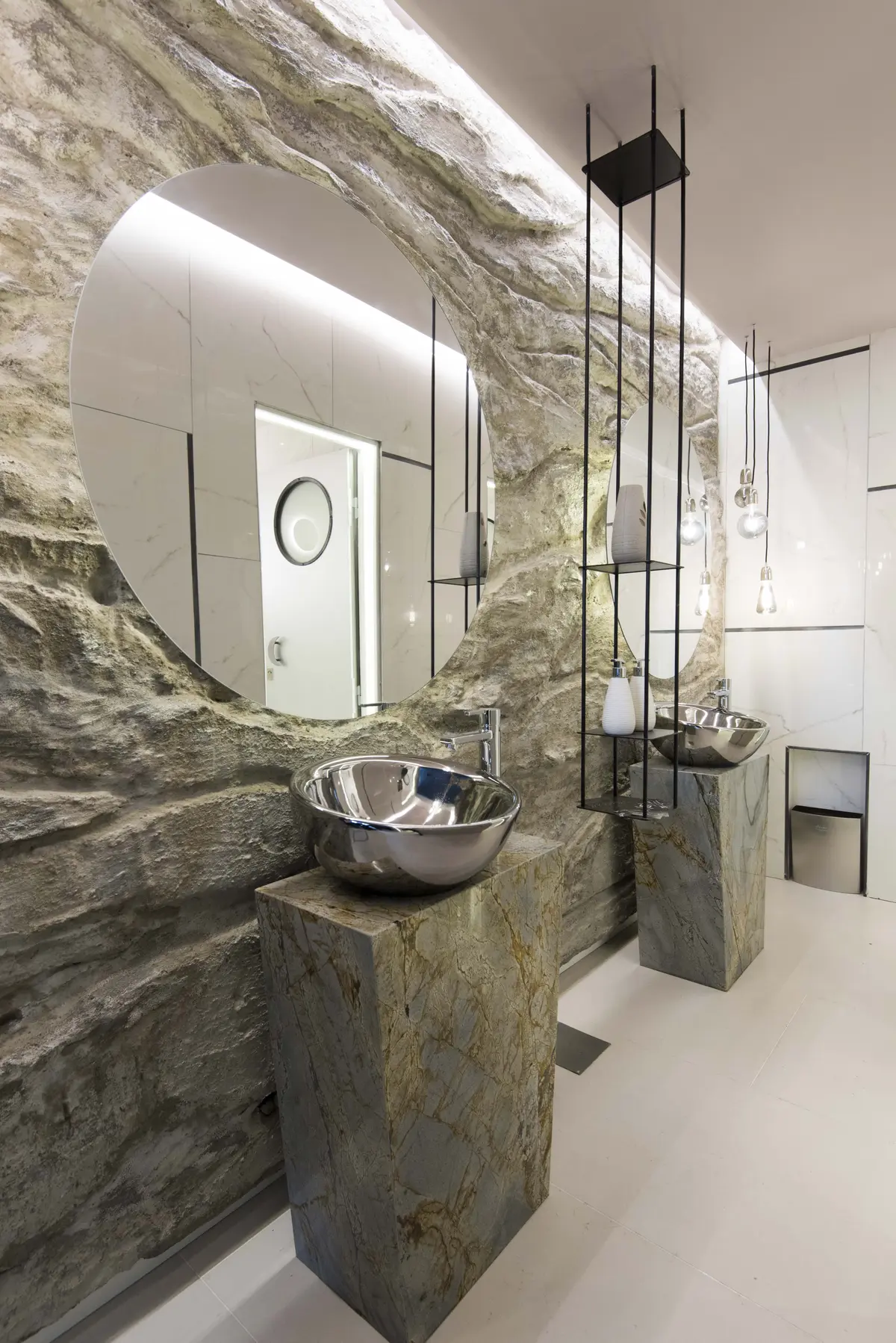 Banheiro moderno com paredes texturizadas de rocha e pias metálicas sobre pedestais de mármore — projeto Eclipse Lunar, por KUPERDESIGN CONSTRUCCIONES SRL, em B1636 Olivos