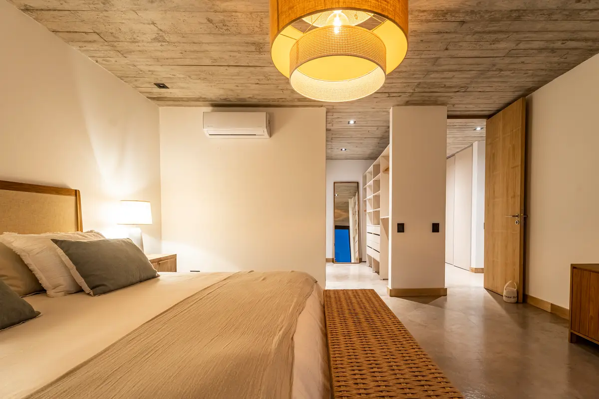 Dormitorio moderno con techo de hormigón visto y luz colgante natural — proyecto CASA sobre el MAR, por Guerrero Arquitectos, en Pinamar