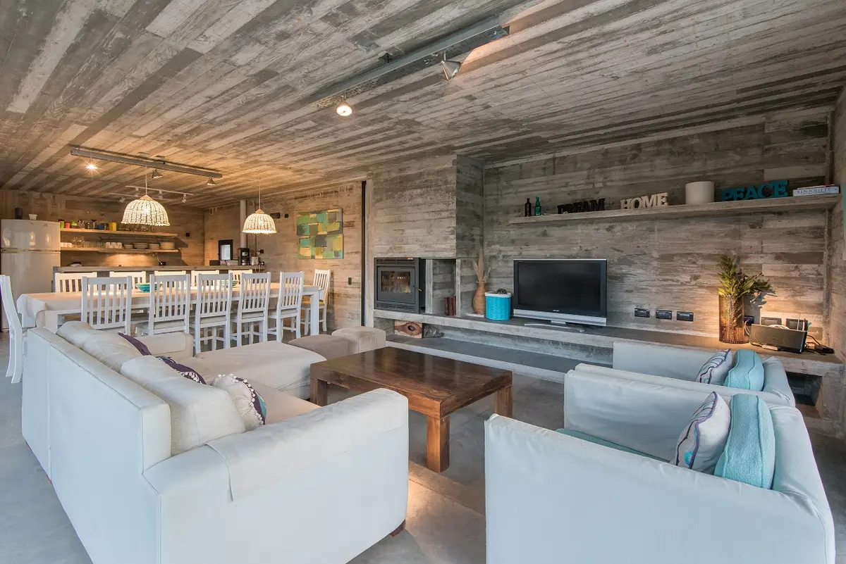 Living moderno industrial con hormigón expuesto y muebles blancos — proyecto Casa R2, por Guerrero Arquitectos, en Pinamar
