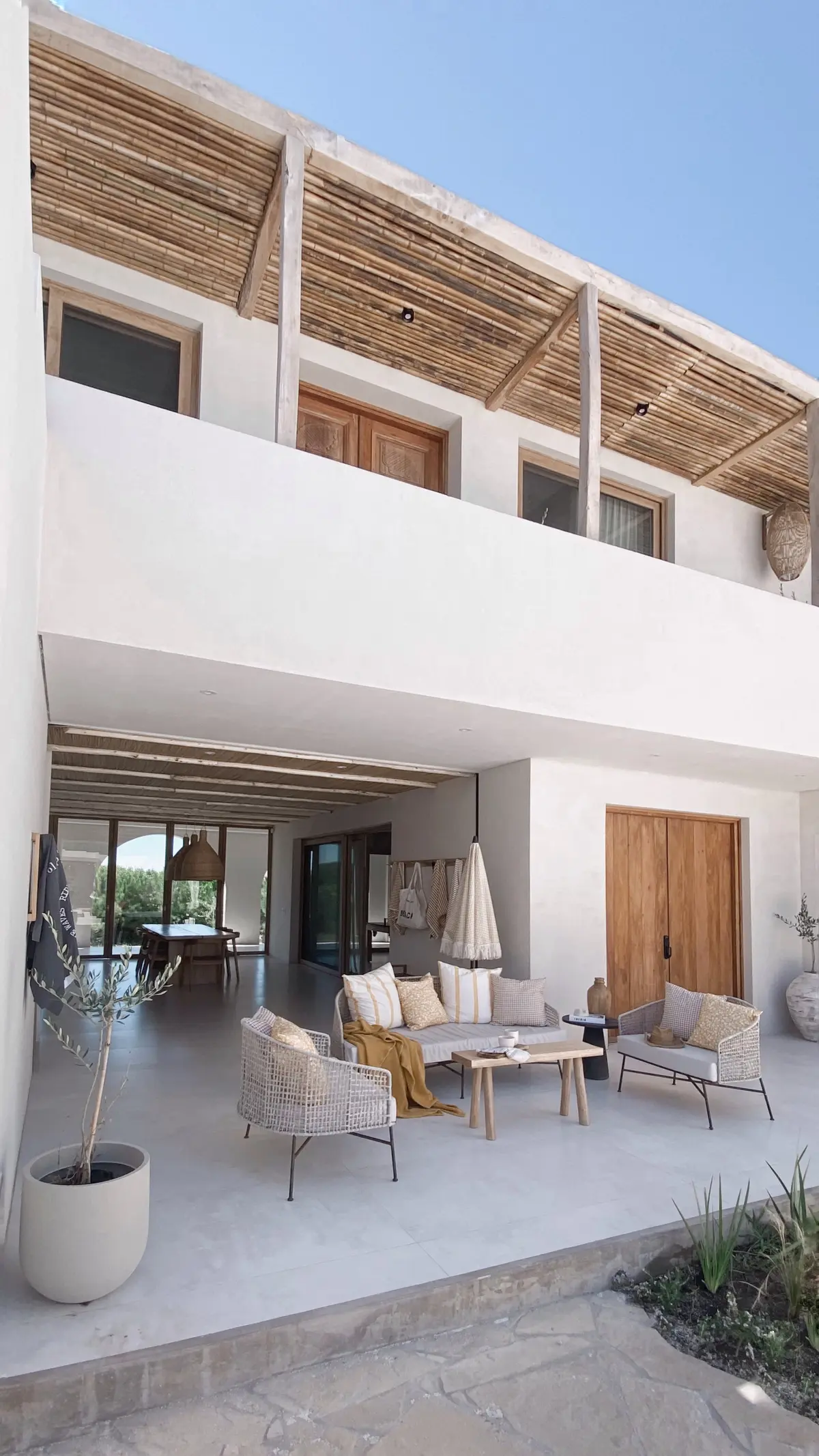 Terraço mediterrâneo com móveis de vime e teto de bambu — projeto El Refugio, por Grupo Pauta Arquitectura, em Pinamar