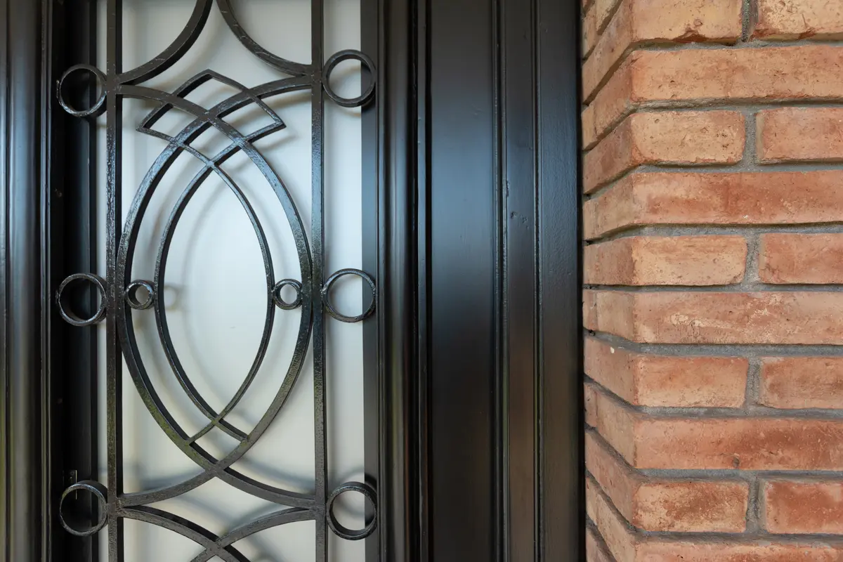detalle de puerta de hierro forjado y fachada de ladrillo — proyecto VIVIENDA L.L, por Lorenabusquetsarquitectura, en Córdoba