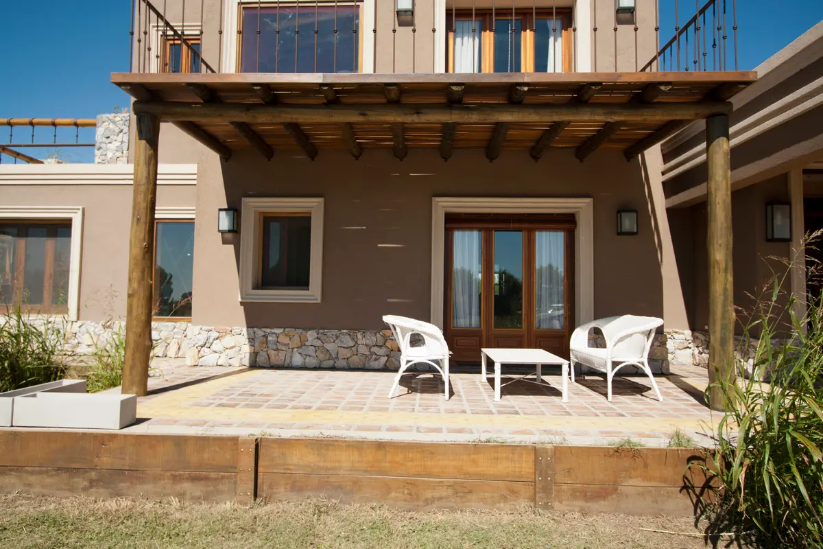 Fachada com pérgola de madeira e área de estar externa mediterrânea — projeto Inmuebles, por Geo Estudio, em Buenos Aires