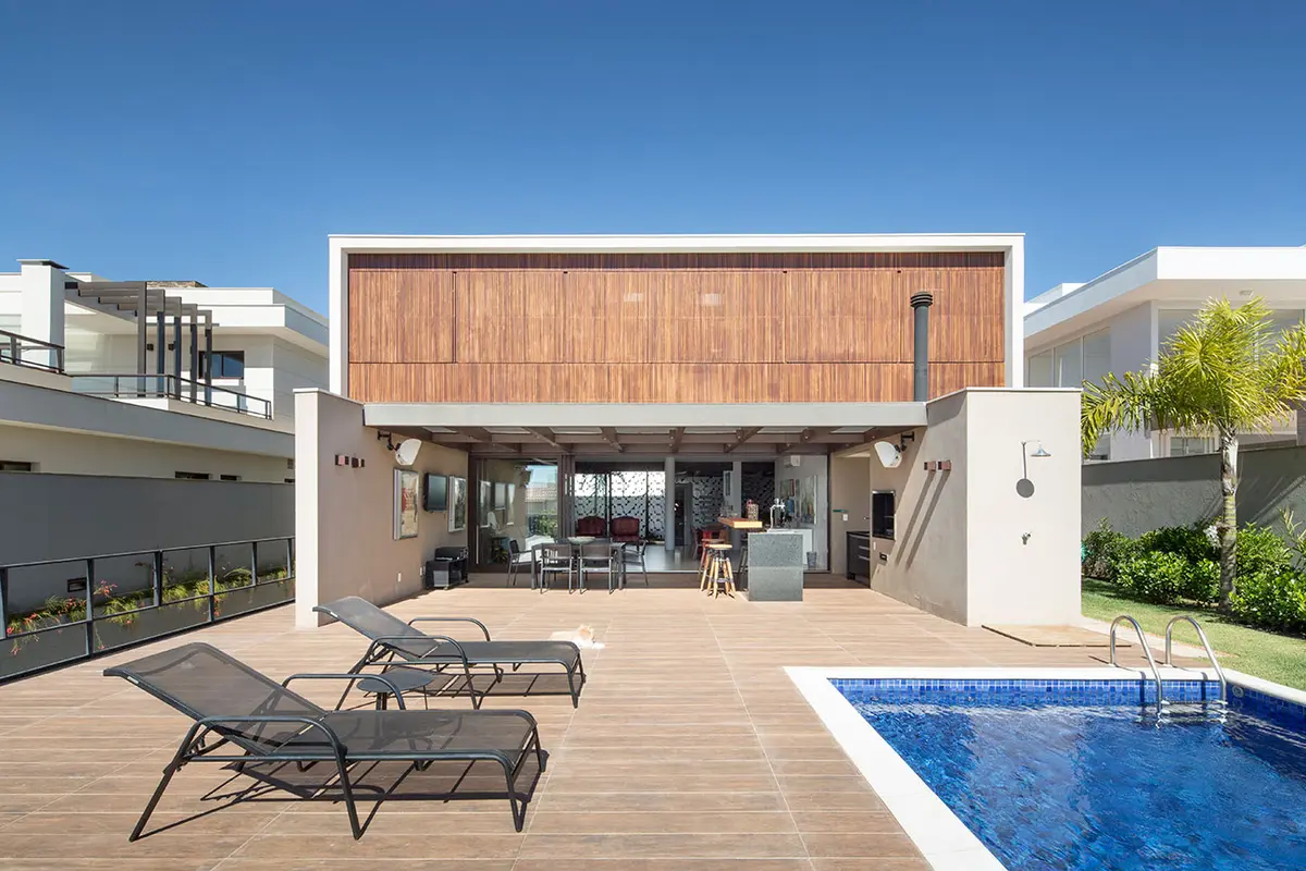Casa moderna com fachada de madeira, deck e piscina — projeto CASA LA, por Esquadra Arquitetos