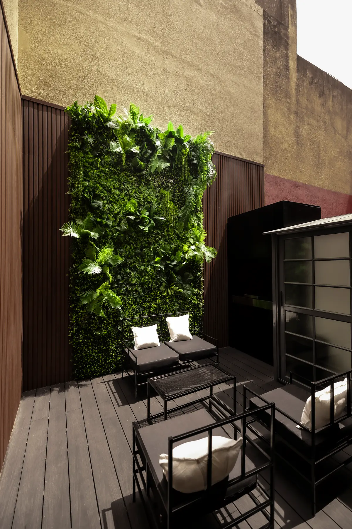 Pátio moderno com parede verde e deck de madeira escura — projeto Jardín vertical  Asunción, por Riumi Botánica, em Buenos Aires