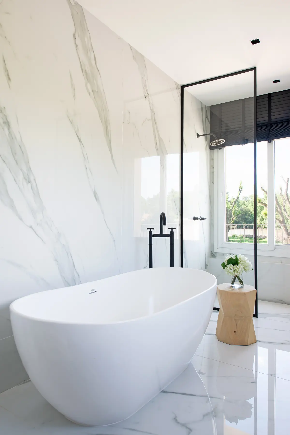 Banheiro moderno com banheira freestanding e paredes de mármore — projeto Santa Maria De Tigre, por Parq Estudio, em Tigre