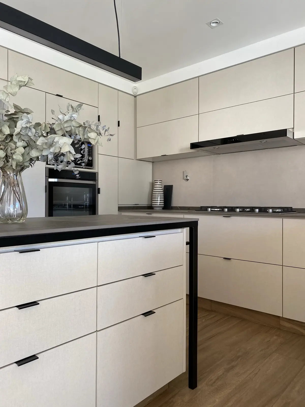 Cozinha moderna com ilha, armários minimalistas bege e detalhes pretos — projeto Casa en Martinez, por JT ARQUITECTURA, em Martínez