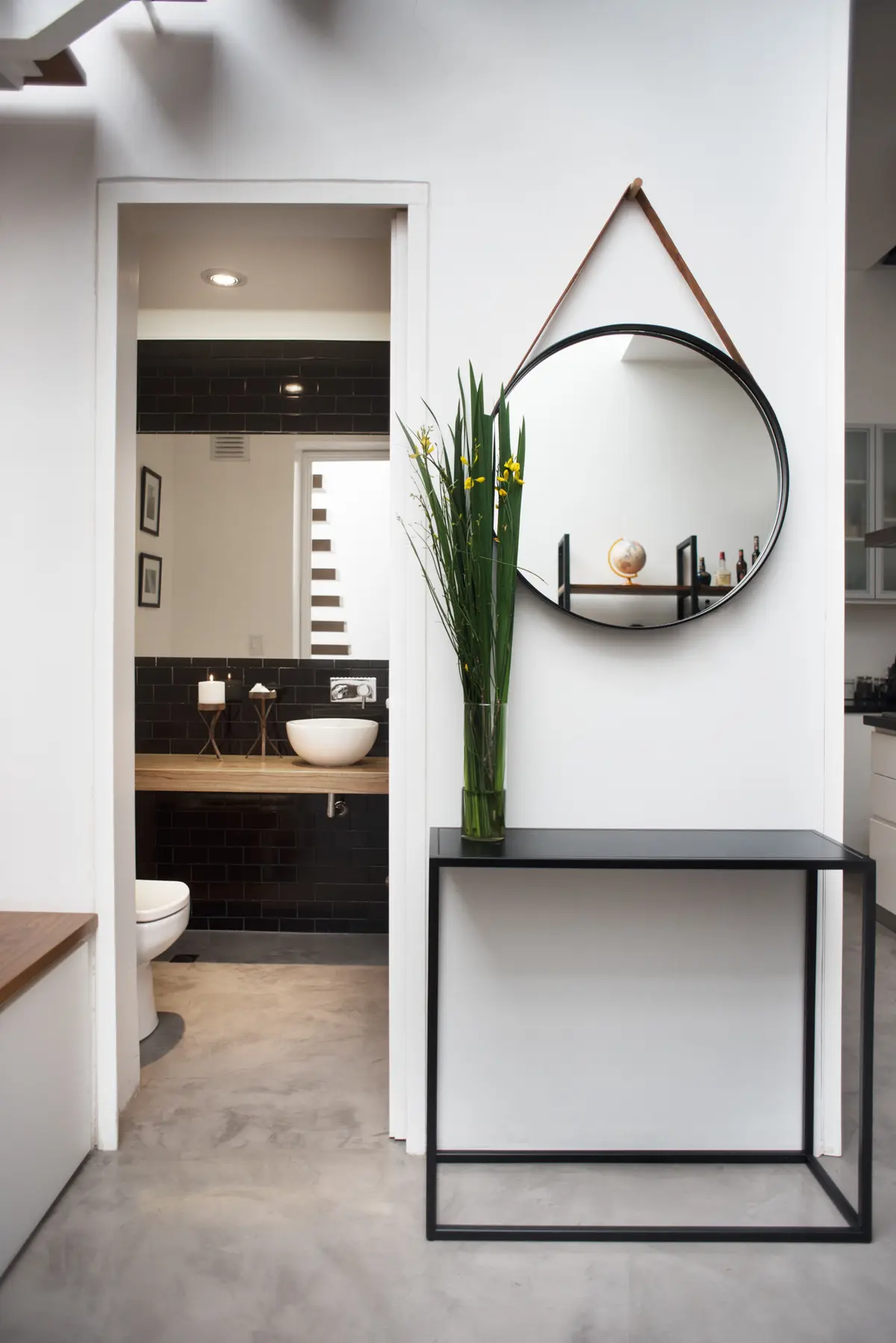 Baño moderno con espejo redondo colgante y consola negra — proyecto Ravignani, por Estudio Basa, en Palermo
