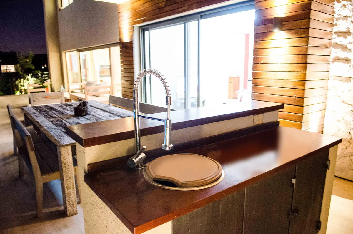 Cocina exterior moderna con isla y detalles en madera — proyecto Casa Nordelta, por linearecta.arquitectura, en Nordelta