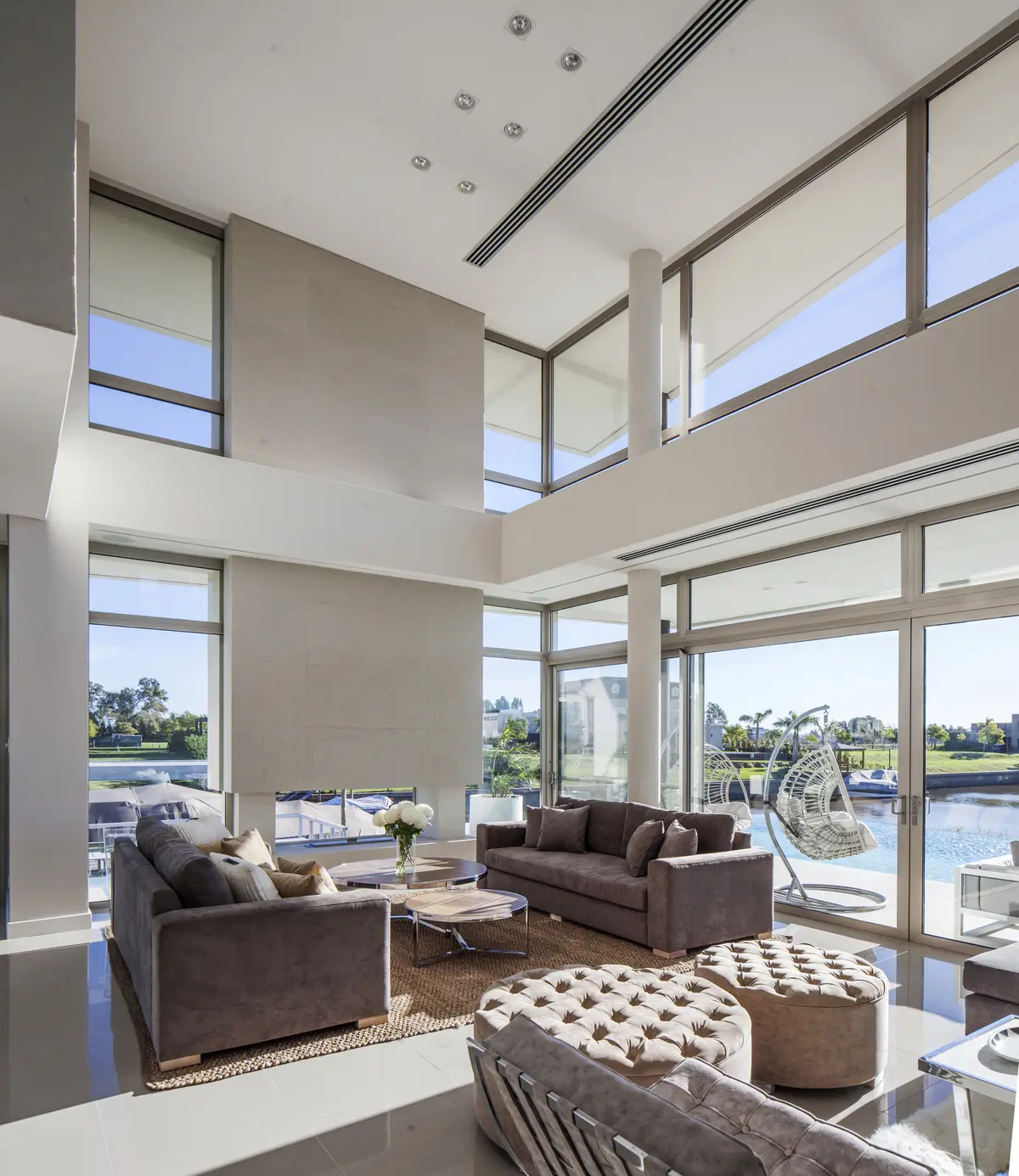 Sala de estar moderna de pé-direito duplo com janelas do chão ao teto — projeto Casa Caledoiscopio, por Apaarquitectura, em Nordelta