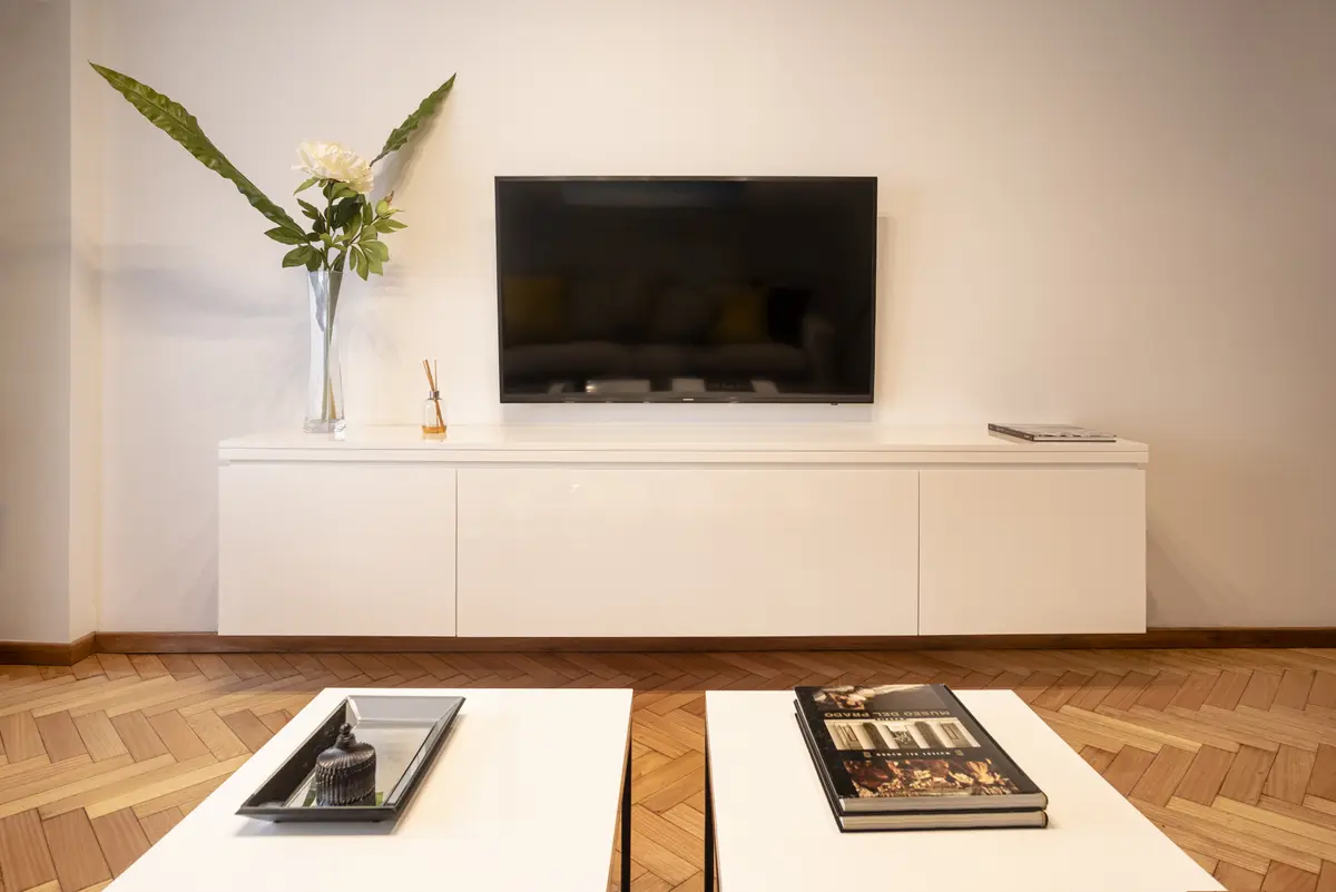 Living moderno con tv grande y mueble bajo blanco — proyecto Austria, por ST Arquitectas, en CABA