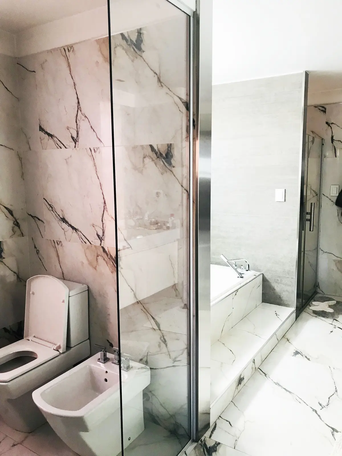 Baño moderno con mármol veteado, inodoro, bidet y bañera empotrada — proyecto Monroe - La Horqueta, por Mgc.arq, en La Horqueta
