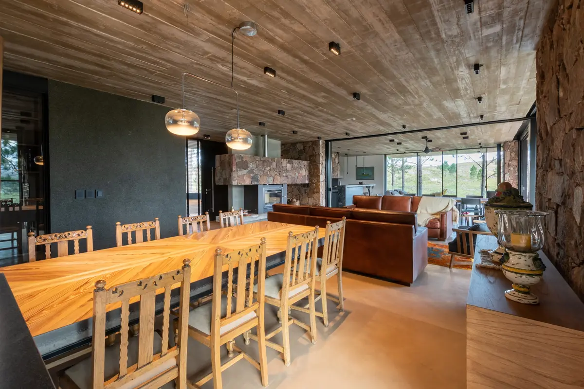 Sala de jantar e estar rústico moderno com teto de concreto e parede de pedra — projeto Vivienda Tanti, por Estudio Qf, em Tanti