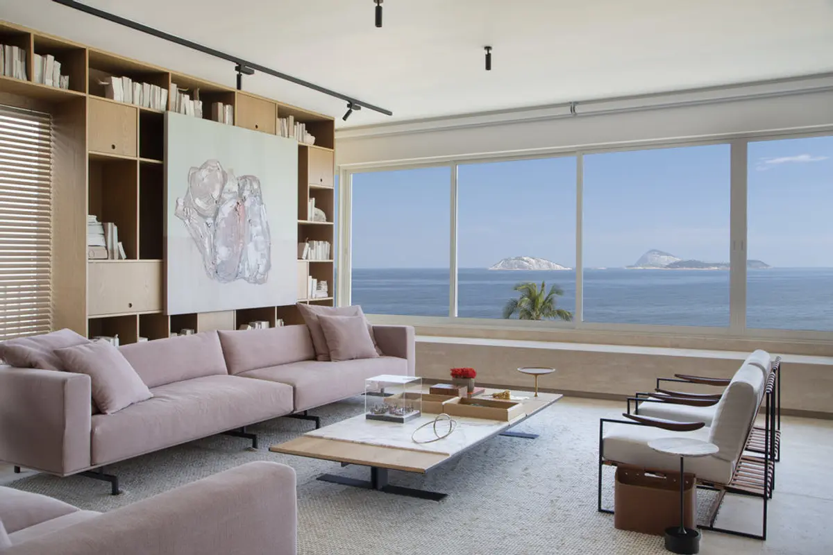 Living moderno con sofá rosa, ventanal al mar y estantería de madera — proyecto PS House, por Studio Ro-ca