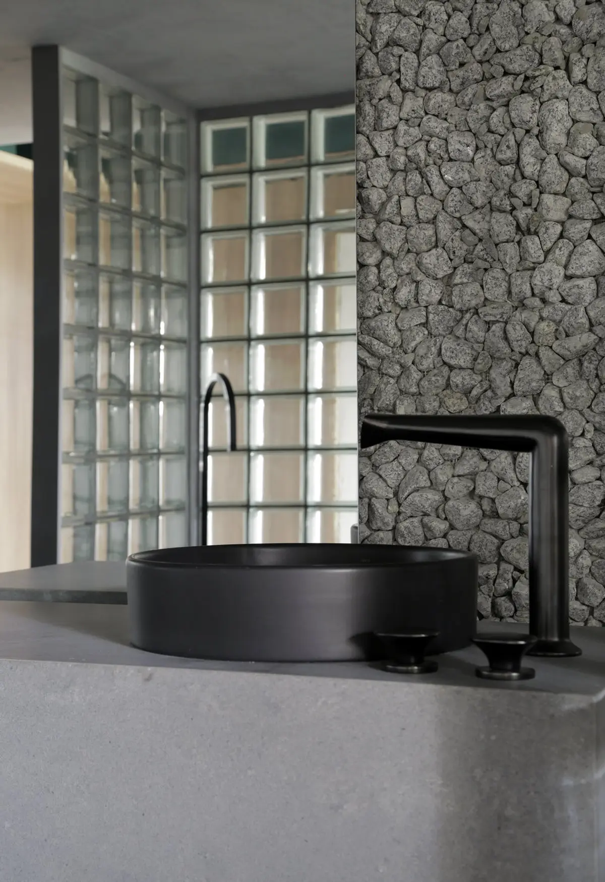 Baño minimalista con bañera negra circular y revestimiento de piedra — proyecto Casa COR 2019, por Studio Ro-ca
