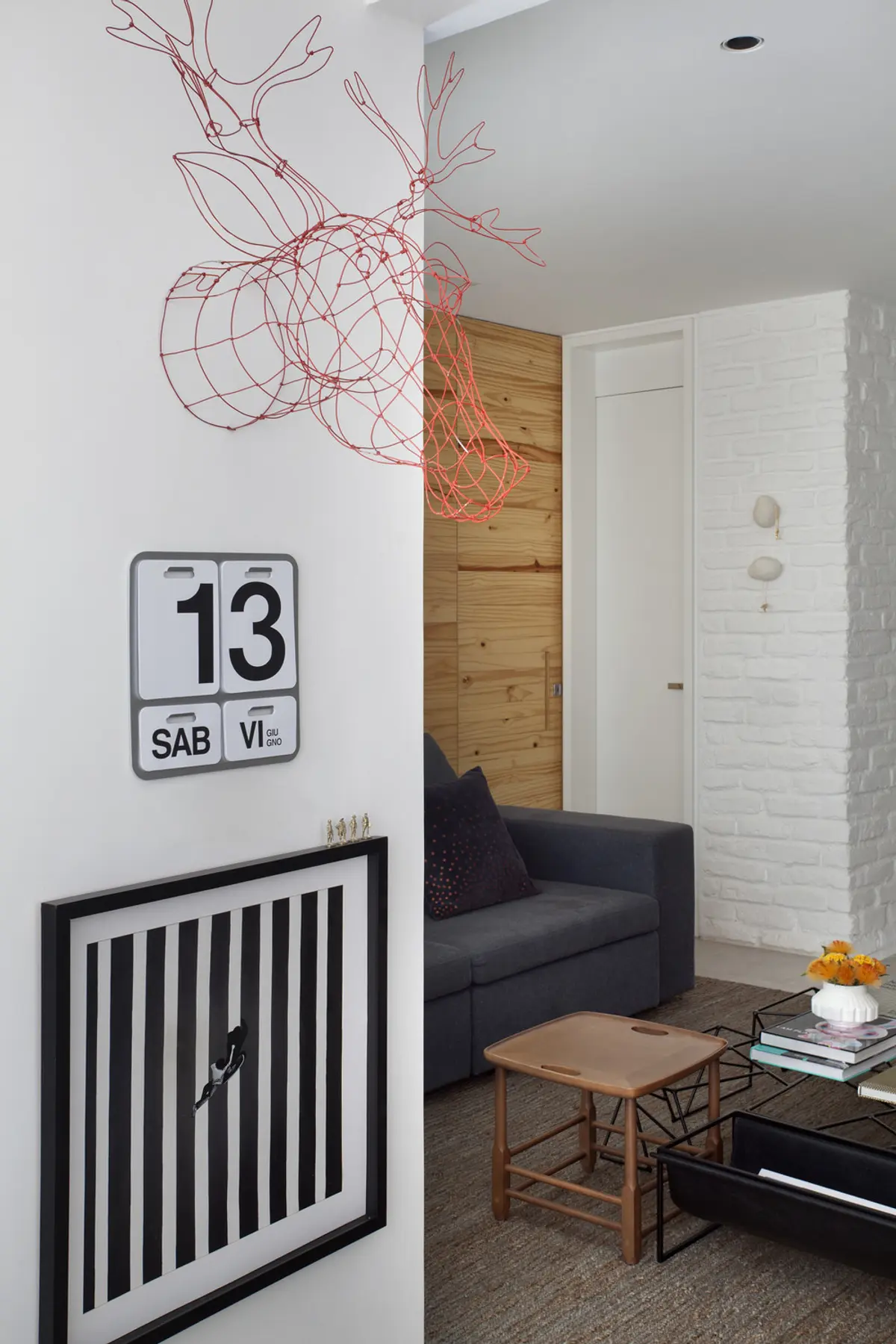 Living moderno con sofá negro, calendario industrial y escultura en pared — proyecto RF House, por Studio Ro-ca