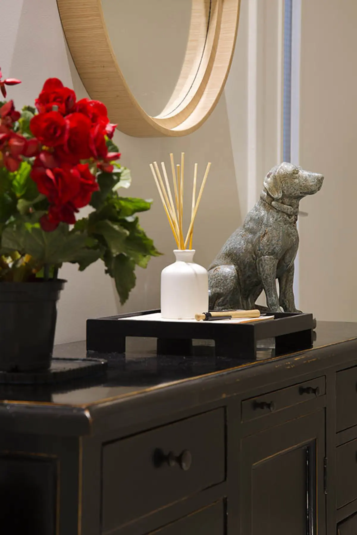Mueble de consola negro con flores rojas y escultura de perro — proyecto Cobertura Arquiteta, por Amanda Miranda
