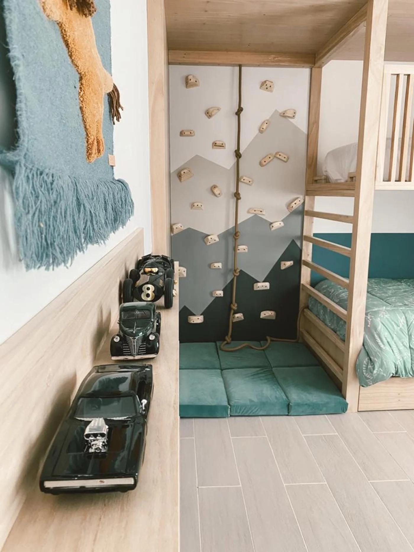 Habitación infantil con litera, rocódromo y estantería de coches de juguete