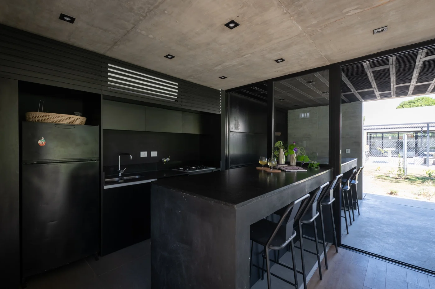 Cocina negra minimalista con isla y vista al exterior