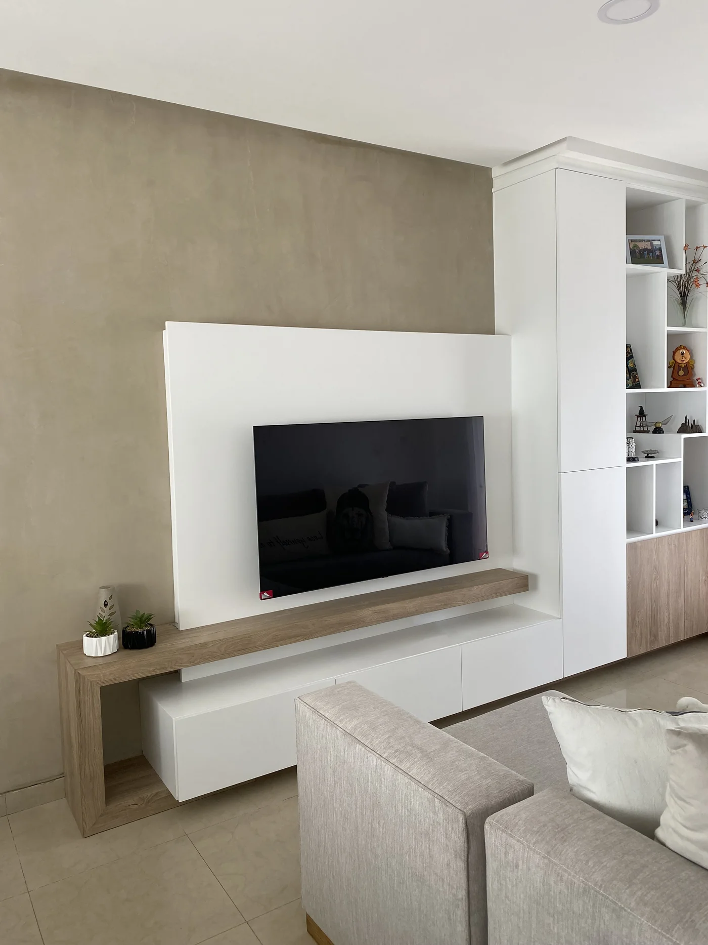 Living moderno con TV empotrada, mueble blanco y pared beige.
