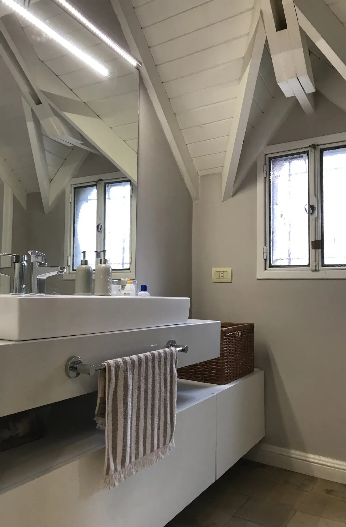 Baño minimalista con doble altura, mesada blanca y tragaluces laterales — proyecto Casa en Martinez, por Rioja Arquitectura, en Martínez