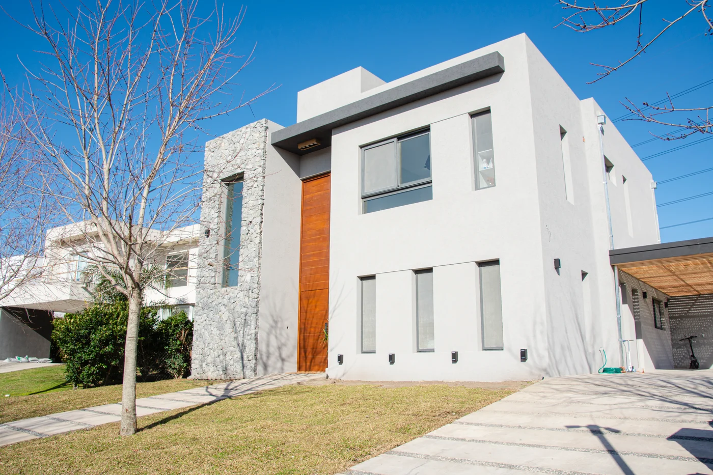Casa moderna de hormigón blanco y piedra gris con grandes ventanales