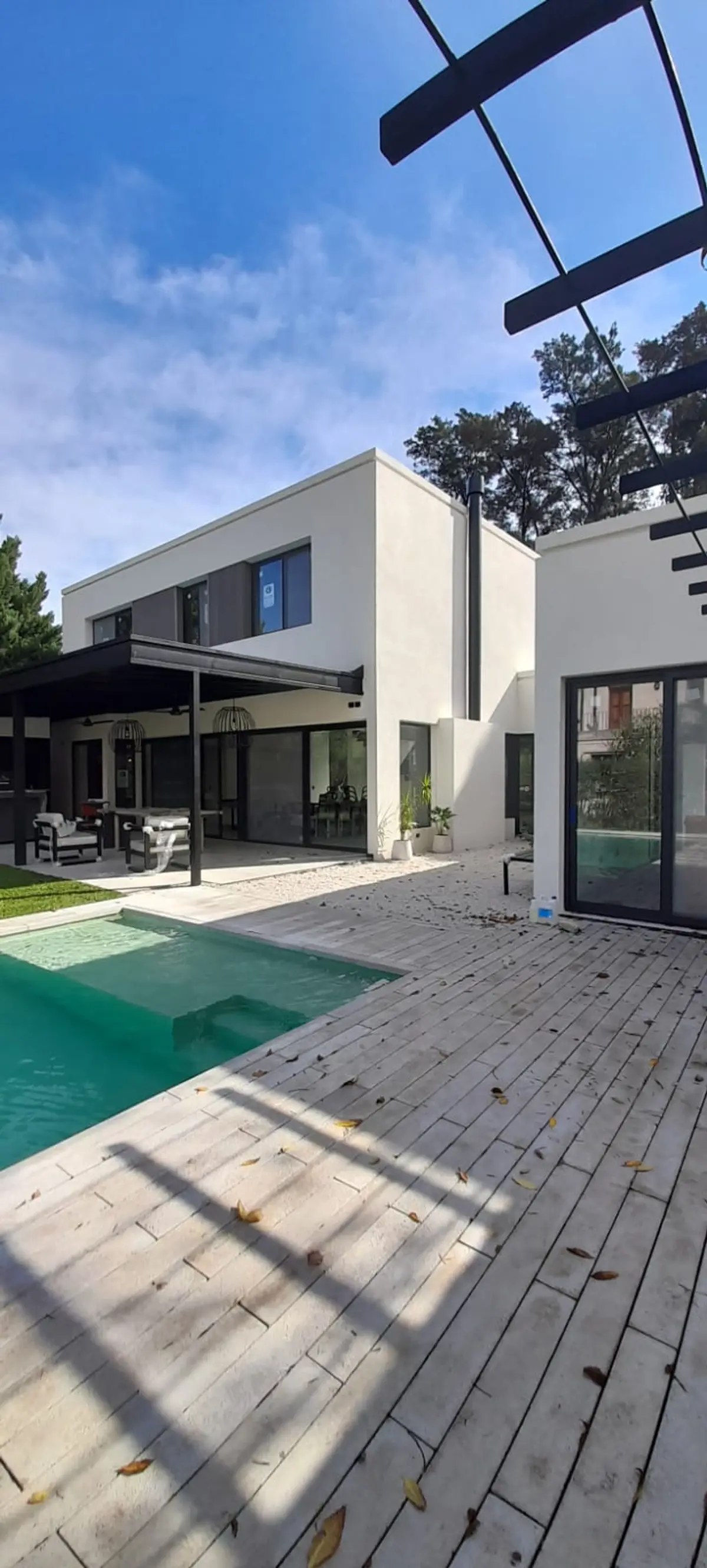 modern casa con piscina y deck de madera — proyecto El 54, por Valeria Damiani Arquitecta, en Pilar