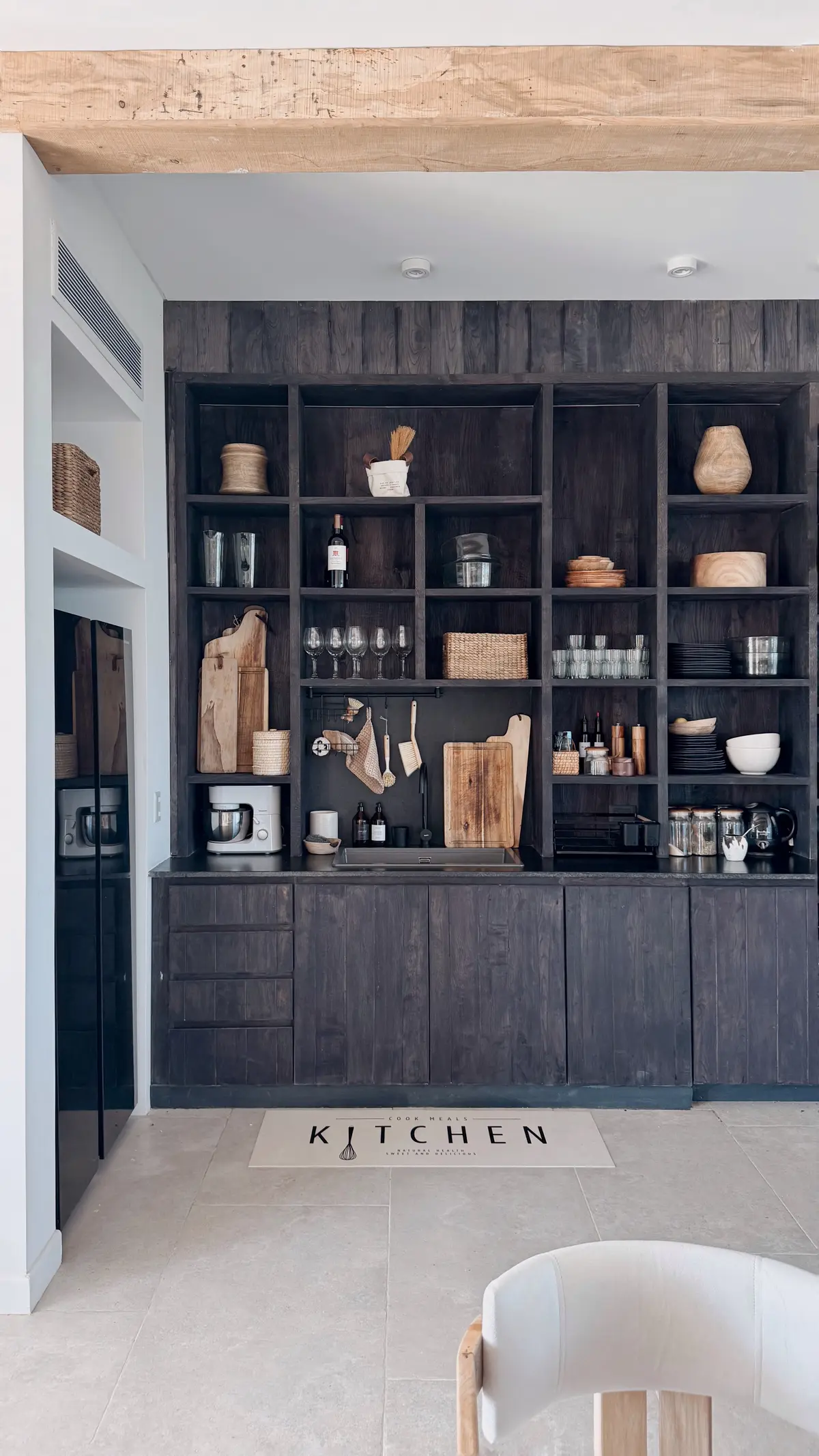 Cozinha rústica moderna com prateleiras de madeira escura e vigas expostas — projeto El Refugio, por Grupo Pauta Arquitectura, em Pinamar