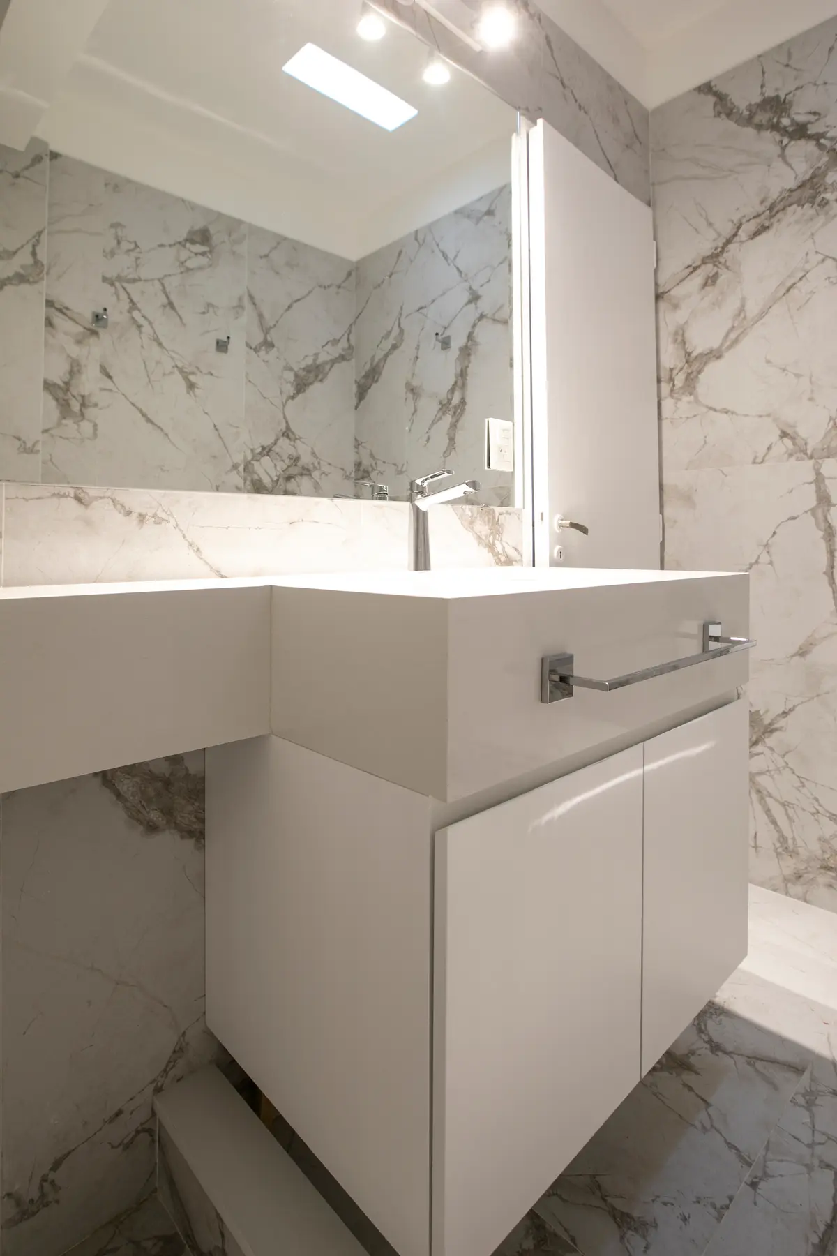 Baño moderno con mármol y vanitory blanco flotante — proyecto Obra Martinez A, por Arq. Lourdes Yarade Saravia, en Martínez