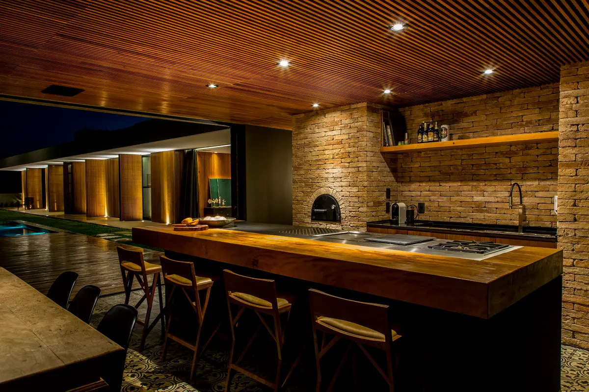 Cozinha externa de luxo com ilha de madeira e teto de ripas — projeto Casa mcny, por MF + Arquitetos