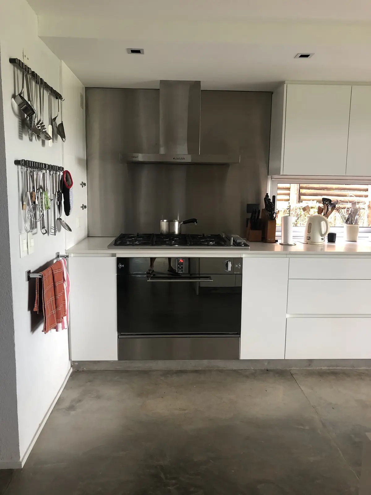 Cocina moderna con piso de microcemento y muebles blancos minimalistas — proyecto MLS3 - Casa en Santa Bárbara, por MLS Estudio, en Benavidez
