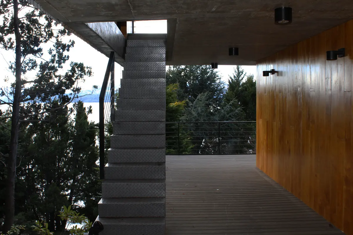moderna escada metálica flutuante sobre deck de madeira — projeto Casa Península San Pedro, por Servente Larrazabal Arq, em Bariloche